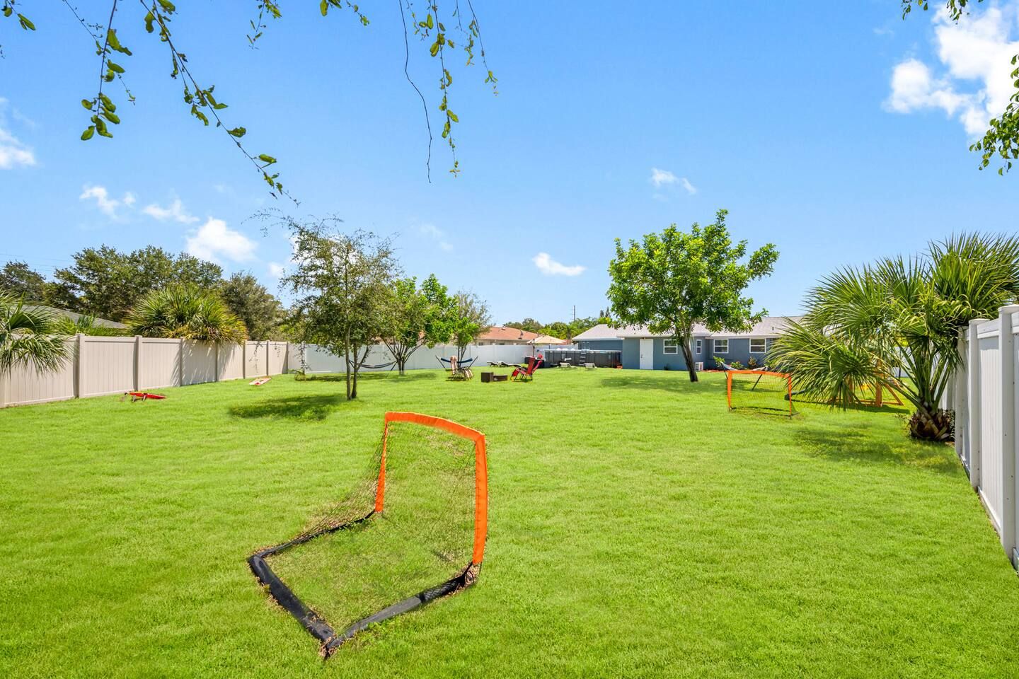 Un jardin bien entretenu avec une pelouse verdoyante, un but de football et un hamac.
