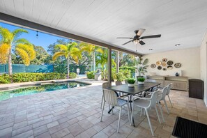A covered outdoor area with a pool, dining table, chairs, ceiling fan, and decorative plates on the wall. - Pool - Pickleball - Basket - Soccer - Game Room! (Seminole)