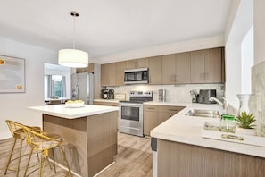 Een moderne keuken met een centraal eiland, roestvrijstalen apparatuur en houten keukenkastjes.