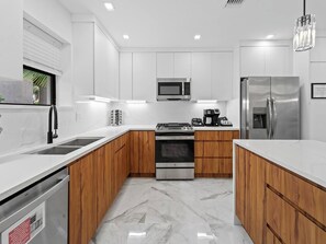 Eine moderne Küche mit weißen Schränken, einem Edelstahl-Kühlschrank, einer Mikrowelle und einem eingebauten Backofen.