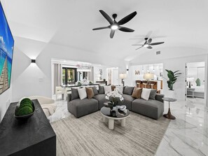 Un saló modern amb un sofà modular, una taula de centre i dos ventiladors de sostre.