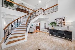 A spacious living area with a curved staircase, a dining area, and a kitchen. - Pool - Pickleball - Soccer - Basket - Sleeps 18! (Tampa)