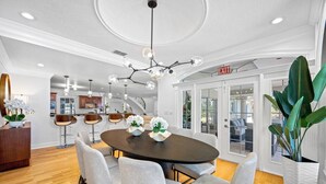A modern dining area with a round table, six chairs, and a chandelier. - Pool - Pickleball - Soccer - Basket - Sleeps 18! (Tampa)
