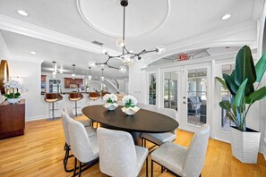 A modern dining area with a round table, six chairs, and a chandelier. - Pool - Pickleball - Soccer - Basket - Sleeps 18! (Tampa)