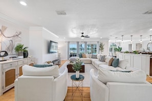 A modern living room with a sectional sofa, a coffee table, and a television mounted on the wall. - Pool - Pickleball - Soccer - Basket - Sleeps 18! (Tampa)