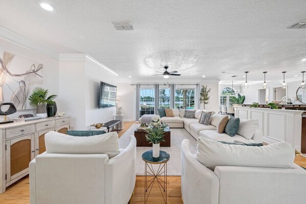 A modern living room with a sectional sofa, a coffee table, and a television mounted on the wall. - Pool - Pickleball - Soccer - Basket - Sleeps 18! (Tampa)