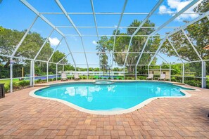 A covered swimming pool with a brick deck, surrounded by a metal frame structure. - Pool - Pickleball - Soccer - Basket - Sleeps 18! (Tampa)