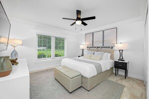 A bedroom with a bed, bedside tables, a ceiling fan, a window with blinds, and a view of greenery outside. - Pool - Pickleball - Soccer - Basket - Sleeps 18! (Tampa)