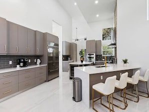Una cocina moderna con una isla central, electrodomésticos de acero inoxidable y taburetes de bar.