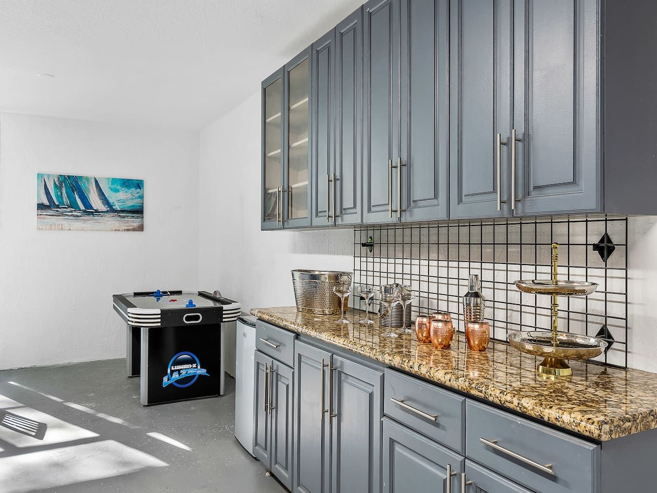 A kitchen with grey cabinets, a granite countertop, and a foosball table.