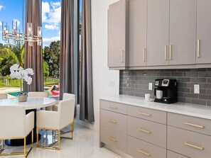 Una cucina moderna con una macchina da caffè, un tavolo da pranzo con sedie e vista su una piscina.