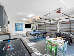 A room with a foosball table, ping pong table, and a table tennis table.