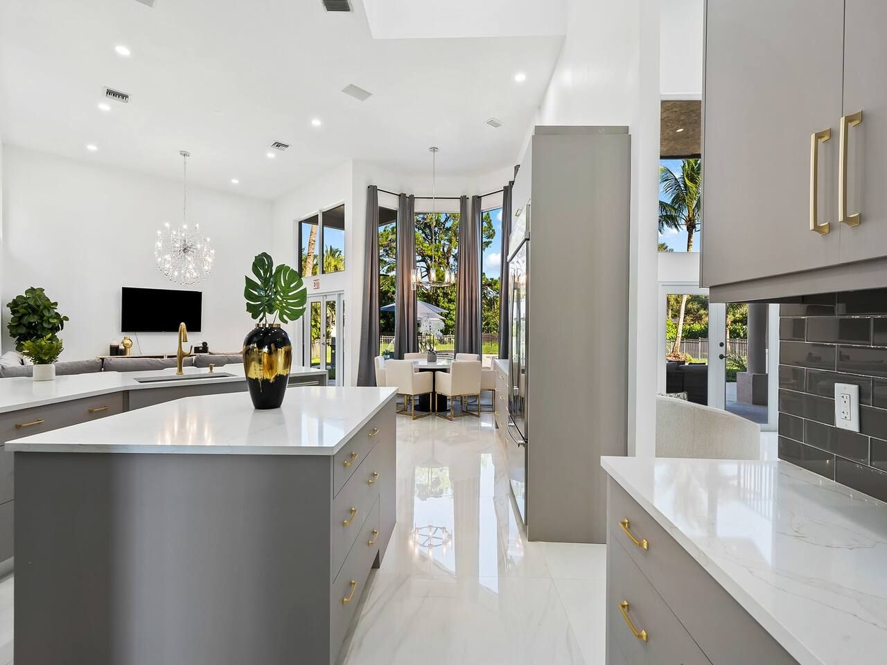 Een moderne keuken met een centraal eiland, grijze keukenkastjes en een eetgedeelte met tafel en stoelen.