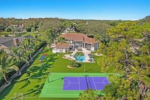 Una propietat residencial amb una pista de tennis, piscina i una casa gran amb terrassa.