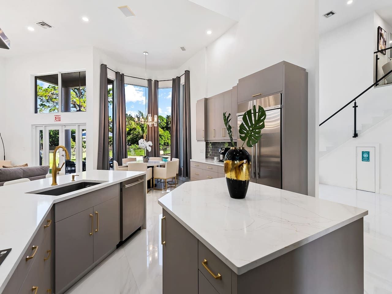 A modern kitchen with a central island, stainless steel appliances, and a dining area with natural light.
