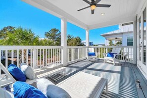 A covered outdoor deck with white railings, lounge chairs, and a ceiling fan. - Sea Mist by Stay on 30a (Inlet Beach)