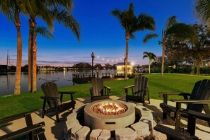 An outdoor seating area with chairs and a fire pit, overlooking a body of water and a dock. - Waterfront - Pool - Pickleball - Basket -Sleeps 18 (Westchase)
