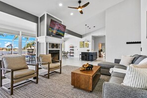 A spacious living area with a fireplace, a television mounted above it, and a ceiling fan. - Waterfront - Pool - Pickleball - Basket -Sleeps 18 (Westchase)