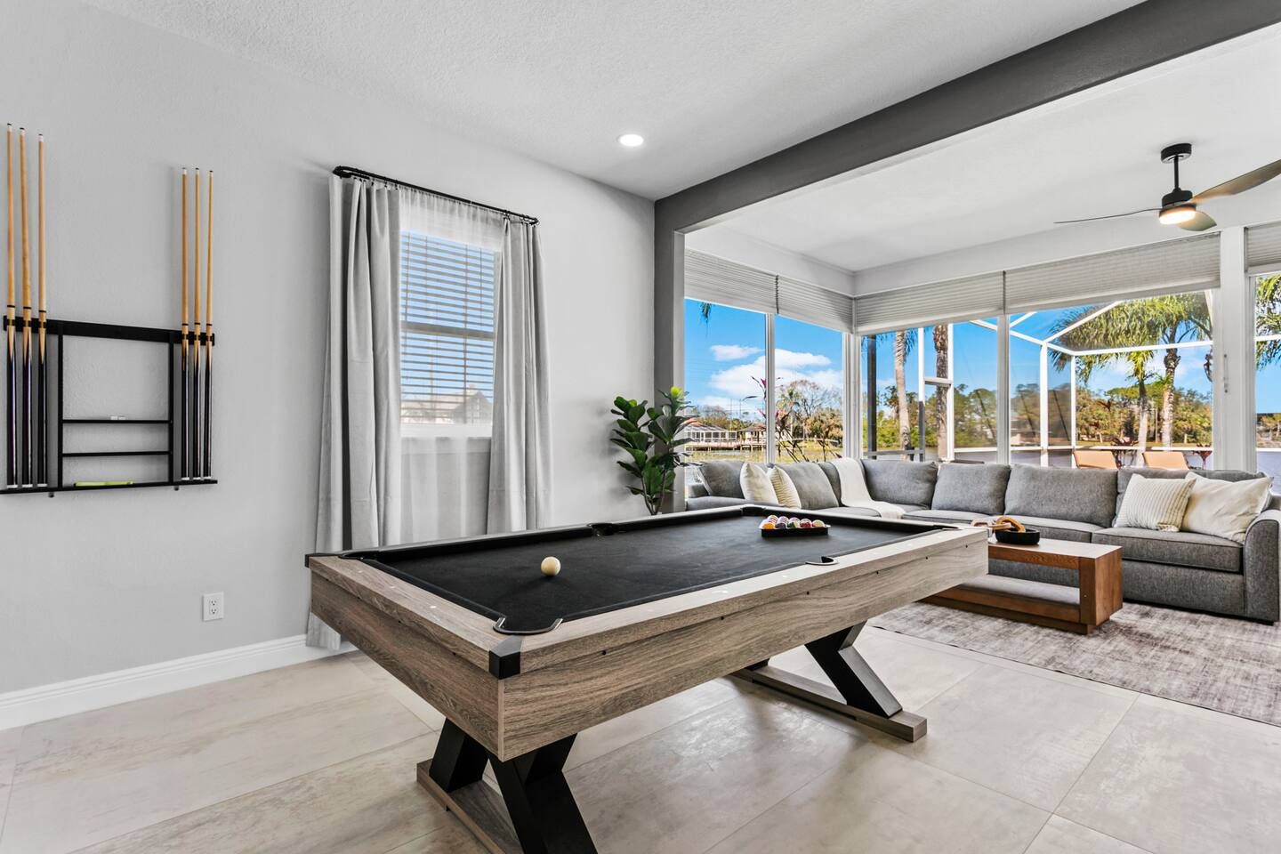 Un salon moderne avec une table de billard, un ensemble de canapés et une vue sur l’extérieur.