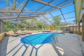 A covered outdoor swimming pool with lounge chairs and a lifeguard tower.