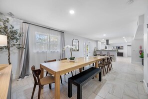 A modern kitchen with white cabinets, a central island, and a dining area with a wooden table and chairs.