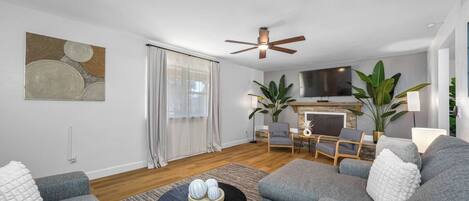 A modern living room with grey sofas, a black coffee table, and a ceiling fan.