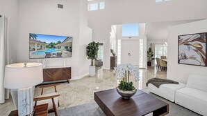 A spacious living area with a flat-screen TV, a dining table, and a sofa.