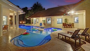 A swimming pool with lounge chairs and a dining area.