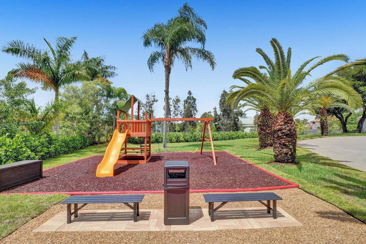 A playground with a slide, swings, and benches.