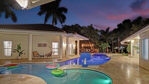 A swimming pool area with multiple pools, lounge chairs, and a covered seating area.