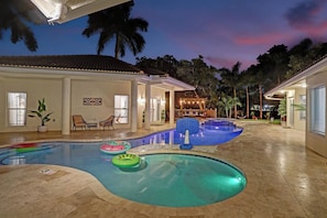 A swimming pool area with multiple pools, lounge chairs, and a covered seating area. - The Grand Luxe 8Br Villa w Pool and Basketball (Pembroke Pines)