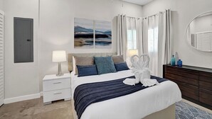 A modern bedroom with a bed, bedside tables, a dresser, a mirror, and a painting on the wall.