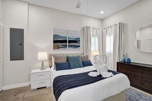 Un dormitorio moderno con una cama, mesitas de noche, un aparador, un espejo y un cuadro en la pared.