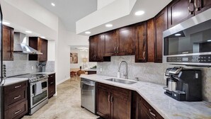 A modern kitchen with dark wood cabinets, stainless steel appliances, and a marble countertop.