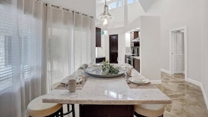 A modern kitchen with a central island, pendant lighting, and a view of the adjacent dining area.