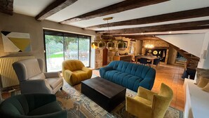 Un vaste espace de vie comprenant un canapé bleu, des fauteuils jaunes et une table basse de couleur sombre.