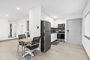 A modern kitchen with white cabinets, a black refrigerator, and a microwave. - Spacious Apartment w/Patio & Mini-Golf (Deerfield Beach)