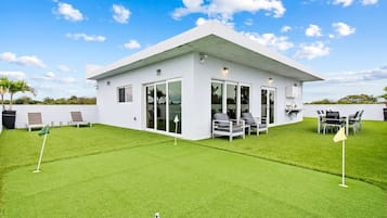 Une maison moderne dotée d’un patio, d’un espace salon extérieur et d’une pelouse bien entretenue.
