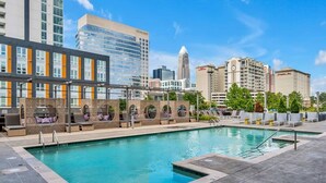A rooftop pool with lounge chairs and a cityscape view. - Skyline Retreat - Free Parking, Pool, Balcony (Charlotte)