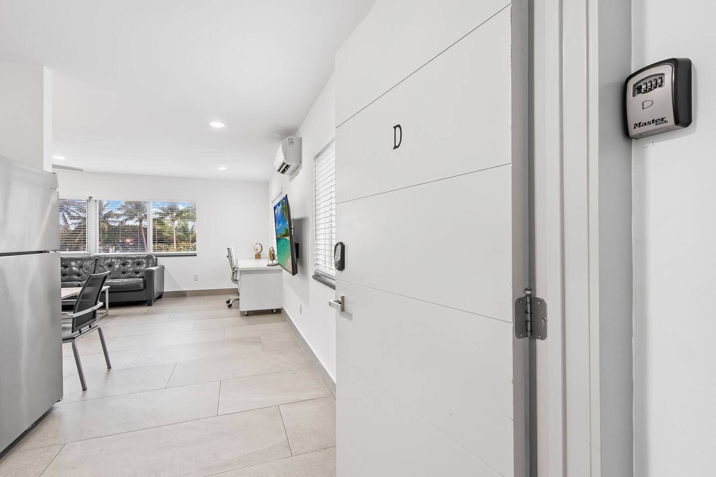 A modern kitchen with white cabinets, a built-in oven, and a refrigerator.