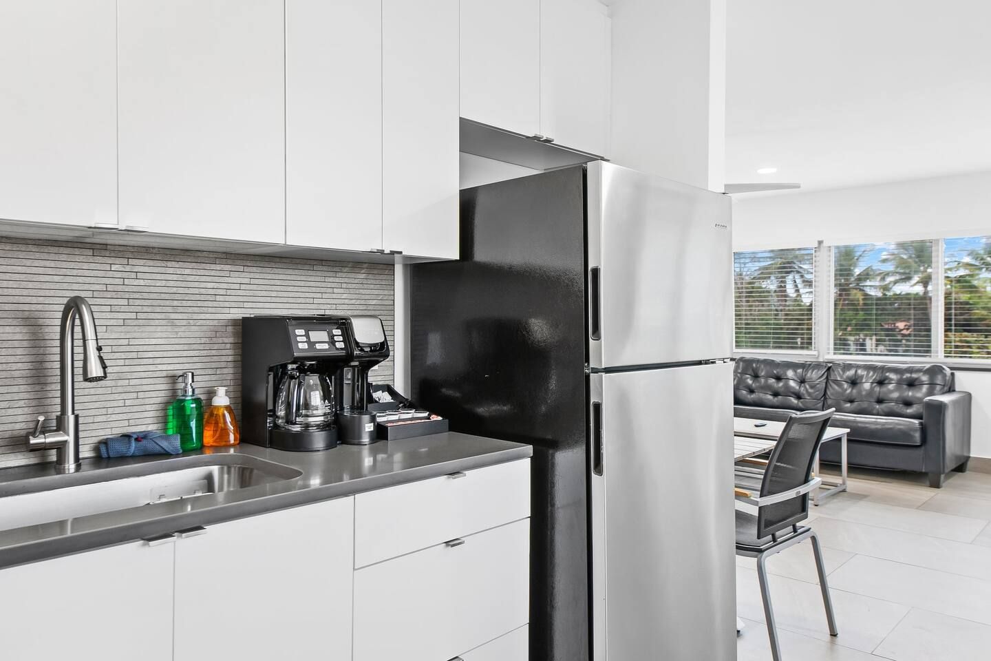 A modern kitchen with a stainless steel refrigerator, a coffee machine, and a sink with a faucet.