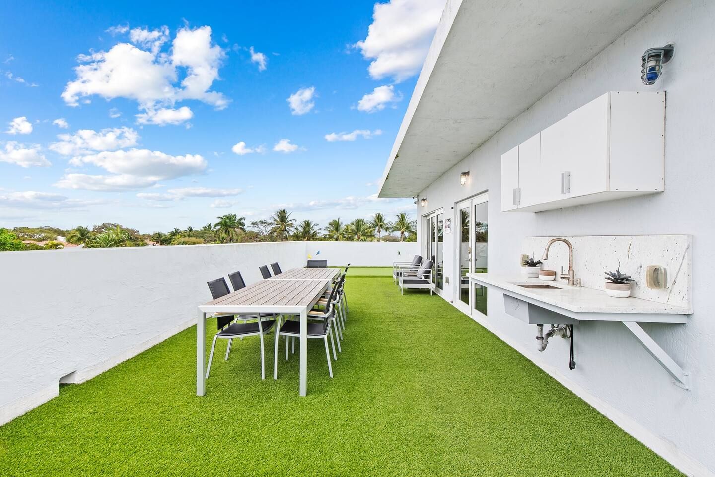 Una terraza en la azotea con una mesa de comedor y sillas, una zona de estar pequeña y una encimera de cocina.