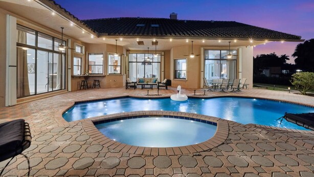 Ein Swimmingpool mit Whirlpool, umgeben von einer Terrasse mit Sitzgelegenheiten und einem überdachten Bereich mit Tischen und Stühlen.