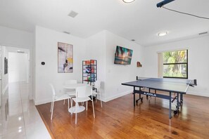 A room with a ping pong table, white chairs, a bookshelf, and artwork on the walls. - Spacious home w/pool & tennis court (Sunrise)