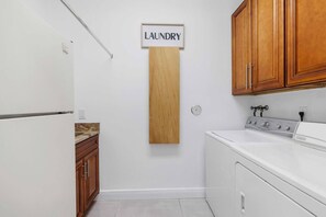 A laundry area with a sign, a refrigerator, a sink, wooden cabinets, and a stove. - Spacious home w/pool & tennis court (Sunrise)
