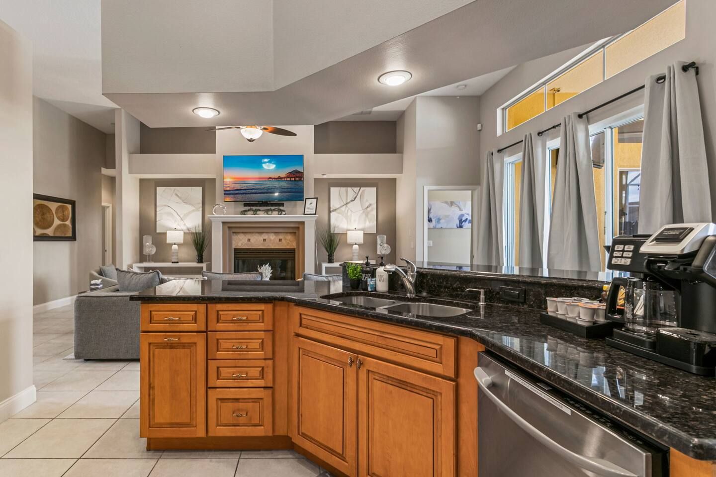 A modern kitchen with a central island, stainless steel appliances, and a large window with curtains.