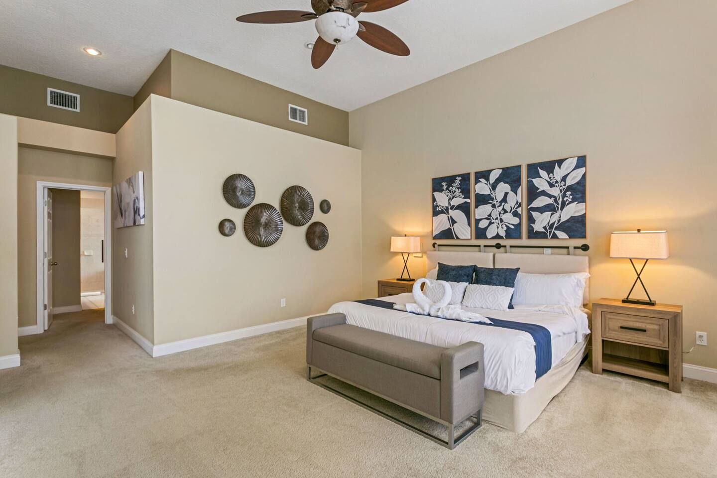 A bedroom with a bed, bedside tables, a ceiling fan, and wall art.