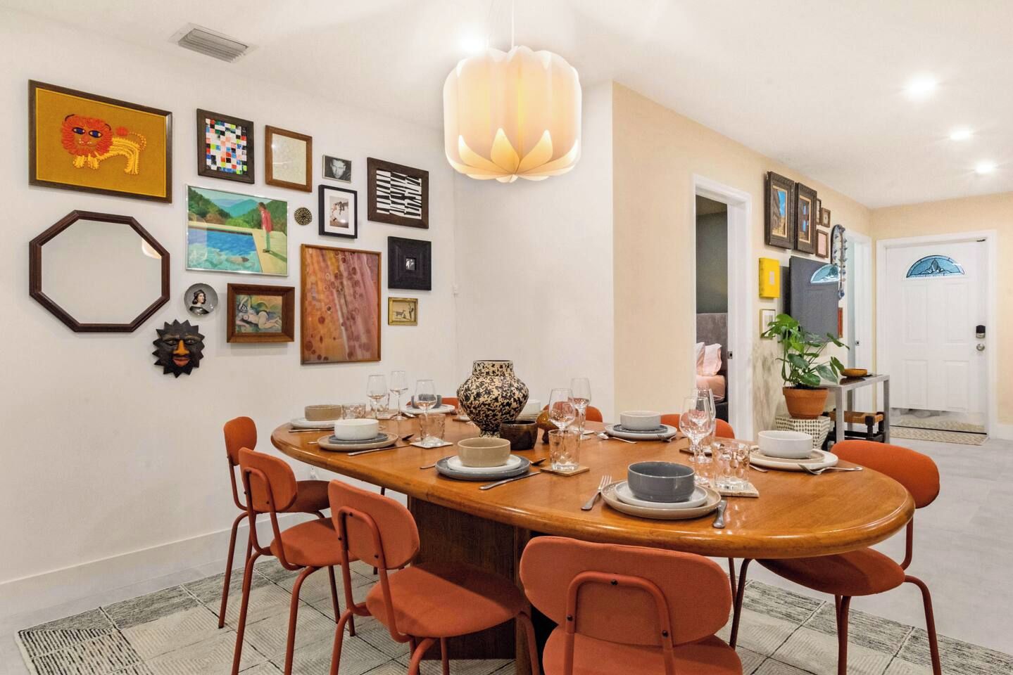 Un coin repas avec une table ronde dressée pour six personnes, entourée de chaises orange.