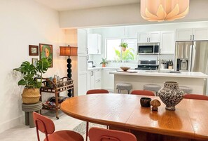 A modern kitchen with white cabinets, a central island, and a dining area with a wooden table and red chairs. - 5 min to beach w/pool & BBQ (Fort Lauderdale)