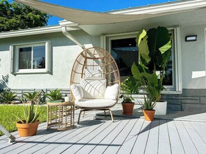 A patio with a wicker chair, potted plants, and a table. - 5 min to beach w/pool & BBQ (Fort Lauderdale)